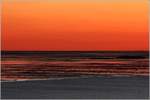 Abendrot über der Wesermündung. Blick von Bremerhaven zur Nordsee: Am unteren Bildrand ist das graue Wasser der Weser zu sehen, darüber das Wattenmeer bei Ebbe. In der linken Bildhälfte leuchtet am Horizont das rote Feuer des Leuchtturms Wangerooge in die aufkommende Nacht. 30.06.2018, 23:13 Uhr.