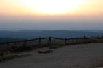 Letztes Abendsonnenlicht auf dem Brocken; Die Sonne ist dabei, hinter einer Wolkenwand in der Ferne zu versinken. Blick vom Gipfelrundweg am Abend des 19.08.2012 Richtung Westen ber den westlichen Oberharz bis zu den Weserberglandschaften am Horizont.