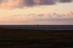 Blick im letzten Abendlicht, von der Neuwarft auf Hallig Nordstrandischmoor, zur Hallig Grde, die auf der Kimm thront. (21.04.2010)
