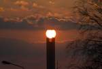 Sonnenaufgang ber dem Schornstein der Stadtwerke.