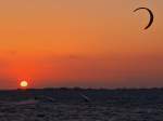 Surfer und Kiter nutzen das letzte Licht des Tages um noch ein paar Schlge ber die Ostsee zu machen. Fr den tollen Sonnenuntergang haben sie keine Zeit, abgebaut wird spter im dunklen am Strand von Albertdorf auf Fehmarn im Mai 2010.