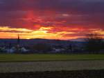 Sonnenuntergang in der Rheinebene, im Vordergrund der Ort Buchheim, rechts im Hintergrund die Vogesen, Dez.2013