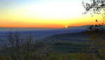 Kaiserstuhl, Blick vom Lenzenberg in die Rheinebene, links im Vordergrund die Häuser vom Weinort Ihringen, die Sonne verschwindet gerade hinter den Südausläufern der Vogesen, Nov.2021