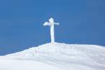 Vom Sturm und Schnee gezeichnet, der an den vorherigen Tagen über die Alpen einherging, ist das Gipfelkreuz des Hahnenköpfle neben dem Hohen Ifen im Kleinwalsertal (Januar 2012)