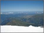 Blick vom schneebedeckten Jungfraujoch auf die schneefreie Bergwelt der Umgebung.