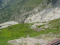 Das wei�liche Gletscherwasser des Rh�negletschers st�rzt sich hier �ber die Felsen hinunter ins Tal, wo man bereits die junge Rh�ne als kleinen Flu� sehen kann, w�hrend sich die Pa�stra�e, von der Furka kommend, in Serpentinen Richtung Gletsch hinabwindet. (11.07.2008)