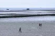 Das Wattenmeer bei Ebbe vom Deich bei Lüttmoorsiel aus gesehen. Im Vordergrund stehen Sie Wattwanderer auf dem weg nach Nordstrandischmoor. Im Hintergrund die Halligbahn nach Nordstrandischmoor und zwei Boote mit neuem Material für die Faschinen. Aufnahme: Mai 2008.