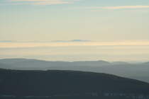 Abendstimmung am 05.12.2016 auf dem Brocken; über dem dunklen Bergrücken des Wurmbergs und südharzer Bergen ragt in der Ferne am Horizont der  Große Inselsberg , der bekannteste Gipfel des Thüringer Walds, ca. 115 km entfernt, aus einem Nebelmeer...