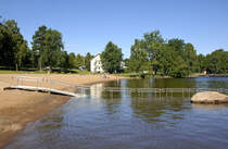 Der Strand »Evedalsbadet« am Halgasjön nördlich von Växjö in Småland / Schweden. Im Hintergrund ist die Jugendherberge von Växjö zu sehen. Aufnahme: 20. Juli 2017.
