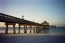 Erst schemenhaft, dann deutlicher l�sen sich die Konturen des Piers aus dem Morgennebel, die aufgehende Sonne verzaubert mit ihrem kupferroten Licht selbst die n�chternen Betonpfeiler des Piers und der Holzzaun, welcher den Laufsteg begrenzt, leuchtet golden in den jungen Morgen - Der Pier in Ft. Myers Beach (FL)