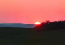 Untergehende Sonne neben Windrädern in der Eifel - 04.03.2022